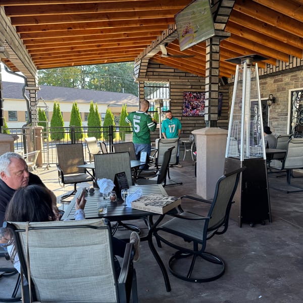Patrons enjoying the outdoor patio at The Palazzo Ristorante, with a pizza box on a table.