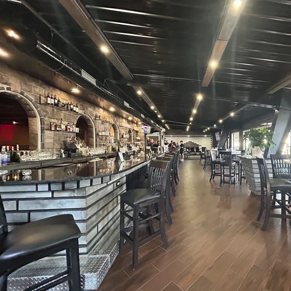The Palazzo Ristorante's interior features a long bar with stools, a stone wall, and dining tables.